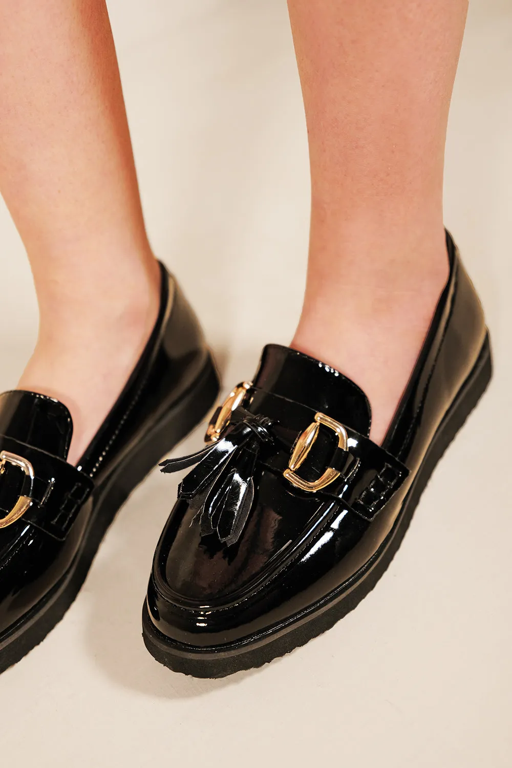 NEDA FLATFROM LOAFERS WITH TASSLE AND METAL DETAIL IN BLACK FAUX PATENT